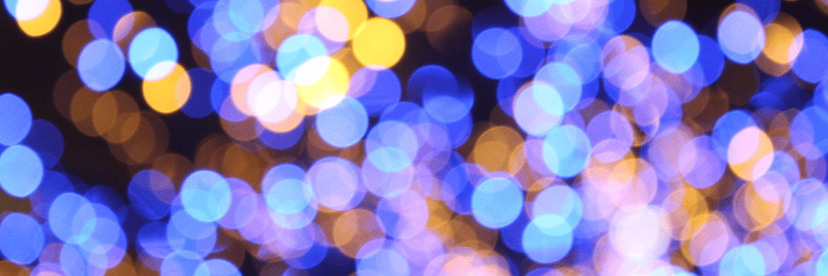 A blurred image of blue and orange bokeh lights creates a dreamy and abstract pattern, almost like inspecting a tapestry of vibrant hues. The soft, out-of-focus circles vary in size, lending the image depth and a festive, celebratory atmosphere.